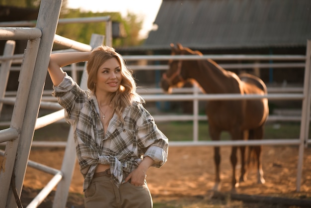 Retrato ao ar livre de uma jovem mulher sexual bonita com cavalo.