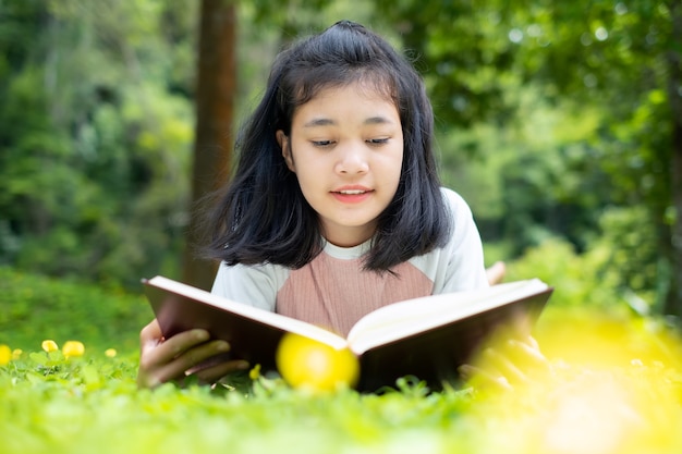 Retrato ao ar livre de uma linda garota jovem, lendo um livro