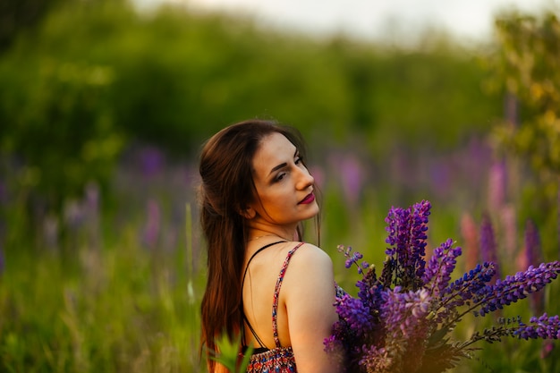 Retrato ao ar livre de uma morena linda jovem idade. garota sexy atraente em um campo com flores