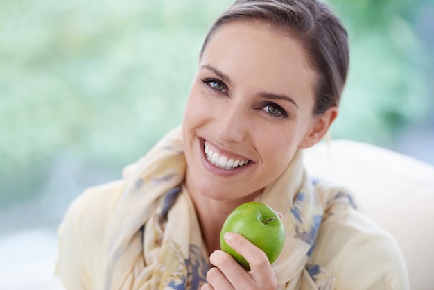 Foto retrato de apartamento o mujer feliz con manzana para una dieta saludable o equilibrada con nutrición o vitaminas silla facial o persona vegana comiendo comida de frutas frescas o fibra para el bienestar orgánico en el salón