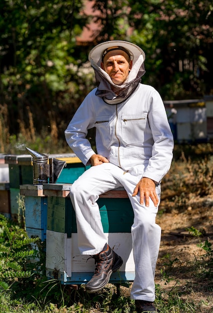 Retrato de apicultor masculino feliz Apicultor está trabajando con abejas y colmenas en el colmenar