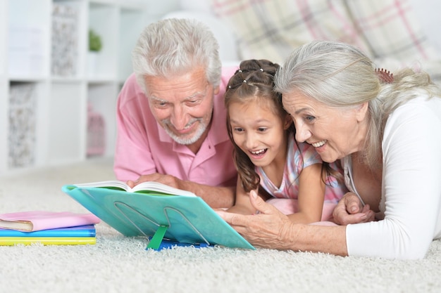 Retrato aproximado de avós lendo livro com neta