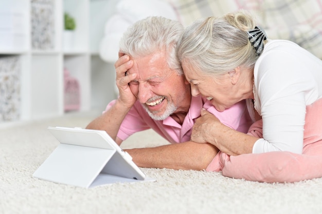 Retrato aproximado de casal sênior feliz usando tablet em casa