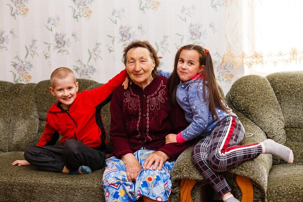 Retrato aproximado de feliz bisavó com bisnetos no sofá em casa