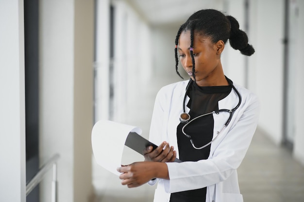 Retrato aproximado de profissional de saúde feminino confiante sorridente amigável com estetoscópio de jaleco Fundo isolado de clínica hospitalar Hora de uma visita ao consultório