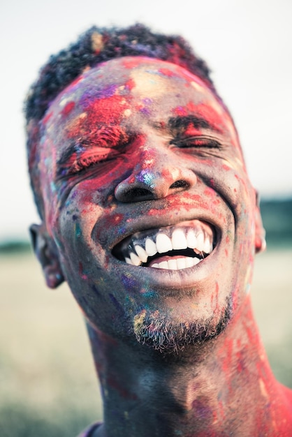 Retrato aproximado de um homem afro-americano feliz com pintura colorida do rosto rindo com o rosto fechado