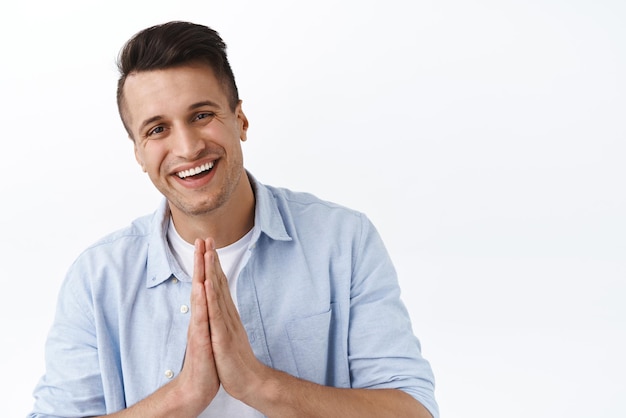 Retrato aproximado de um jovem bonito sorridente, amigável e agradecido, agradecendo ao show namaste bow alegremente faça rezar gestutre grato pela ajuda em pé de fundo branco entusiasmado