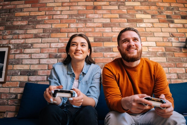 Foto retrato aproximado de um jovem casal feliz e alegre segurando controladores e jogando videogame no console sentados juntos