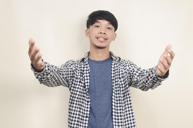 Retrato aproximado de um jovem modelo asiático feliz vestindo camisa xadrez esticando os braços para abraçá-lo