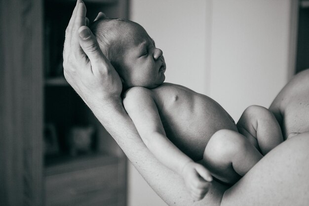 Retrato aproximado de um jovem pai feliz abraçando e beijando seu doce e adorável filho recém-nascido imagem conceitual de tiro interno