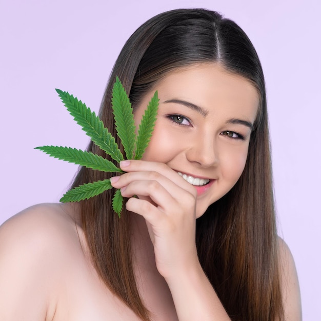 Retrato aproximado de uma encantadora garota gorda com pele fresca segurando folha de cannabis