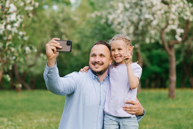 Retrato aproximado de uma família feliz de dois pais sorridentes e uma filha de seis anos pegam um smartphone selfie