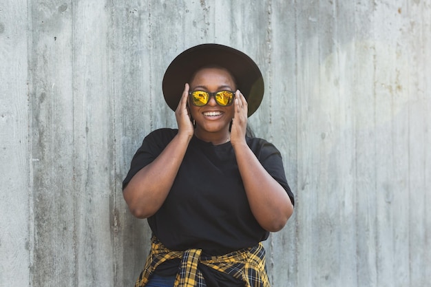 Retrato aproximado de uma garota afro-americana engraçada e estilosa com cabelo encaracolado em óculos de sol da moda em fotos urbanas de hipster de verão com estilo instagram