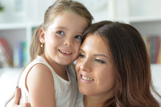 Retrato aproximado de uma garotinha encantadora abraçando com a mãe