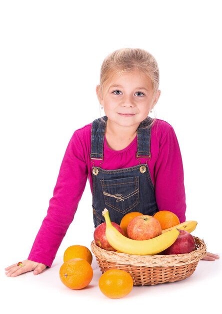 Retrato aproximado de uma garotinha segurando frutas maçãs bananas e laranjas isolado em um fundo leve