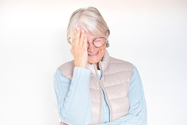 Retrato aproximado de uma idosa de cabelos brancos rindo tocando sua testa com a mão