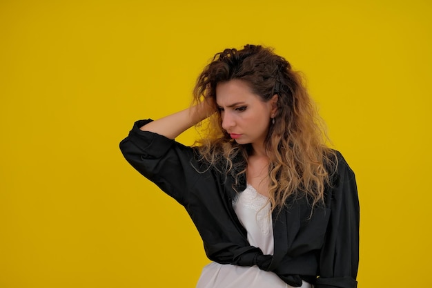 Retrato aproximado de uma linda garota em uma mulher de fundo amarelo mostra emoções humanas de consideração