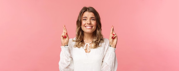 Retrato aproximado de uma linda loira esperançosa fazendo desejo antecipando resultados importantes cruzando fi