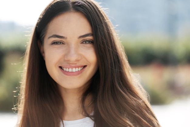 Retrato aproximado de uma linda mulher sorridente com lindos olhos e cabelos longos olhando para a câmera