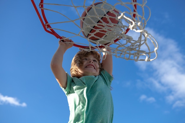 Retrato aproximado do jogador de basquete infantil fazendo slam dunk durante o jogo de basquete