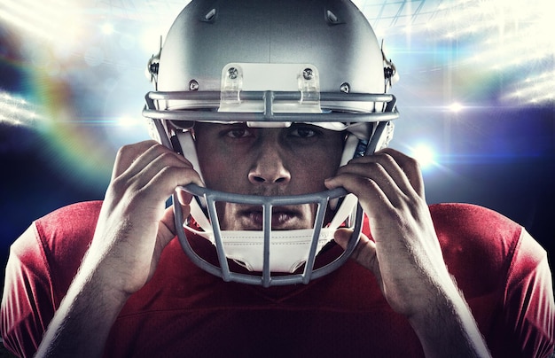 Retrato aproximado do jogador de futebol americano segurando o capacete contra a arena de futebol americano