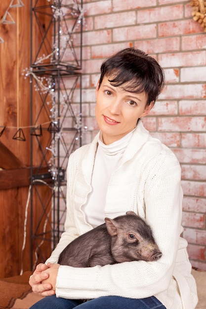 Retrato aproximado, mulher morena feliz, funcionária do banco abraçando o símbolo do ano novo chinês porquinho preto isol