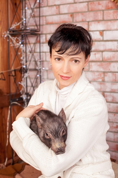 Retrato aproximado, mulher morena feliz, funcionária do banco abraçando o símbolo do ano novo chinês porquinho preto isol