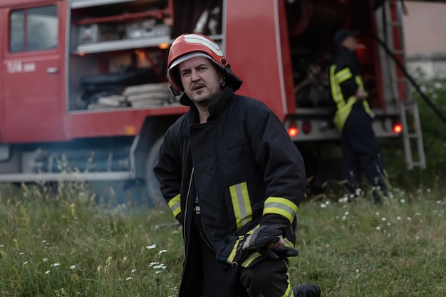 retrato de un apuesto bombero deprimido y cansado cerca del camión de bomberos. foto de alta calidad