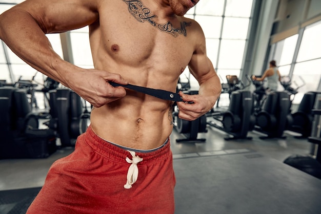 Retrato apuesto y confiado joven caucásico en el fondo del gimnasio Cara de brutal musculoso sexy masculino Está sudando después de hacer ejercicio físico saludable y estilo de vida atlético gente copia espacio