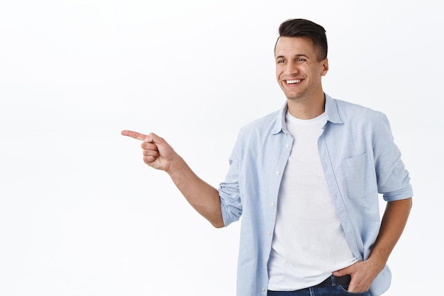 Retrato de un apuesto hombre adulto señalando con el dedo a la izquierda y sonriendo feliz mostrando a un niño el camino a seguir satisfecho recogiendo artículos en la tienda de compras con la familia de pie fondo blanco recomendar producto