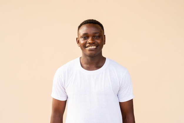 Retrato de un apuesto hombre africano con camiseta blanca mientras sonríe