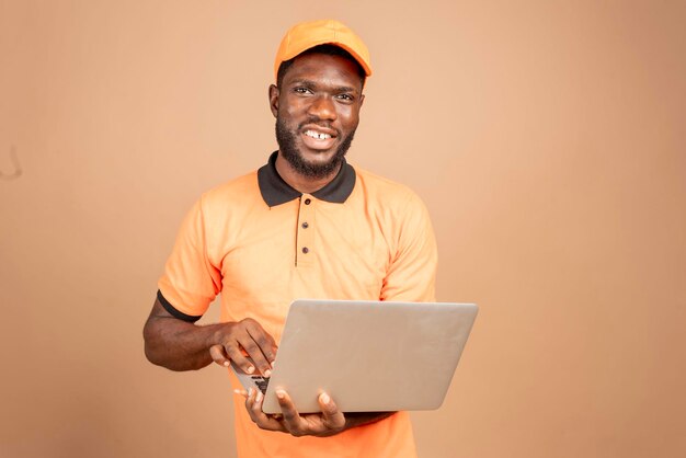 Retrato de un apuesto hombre africano riendo trabajando con una computadora portátil