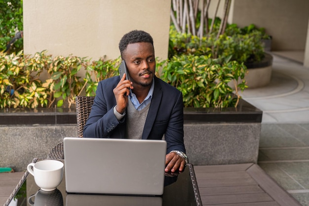 Retrato de un apuesto hombre de negocios africano negro que usa una computadora portátil