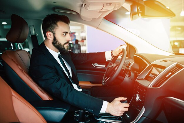 Retrato de un apuesto hombre de negocios sonriente y positivo conduciendo su auto