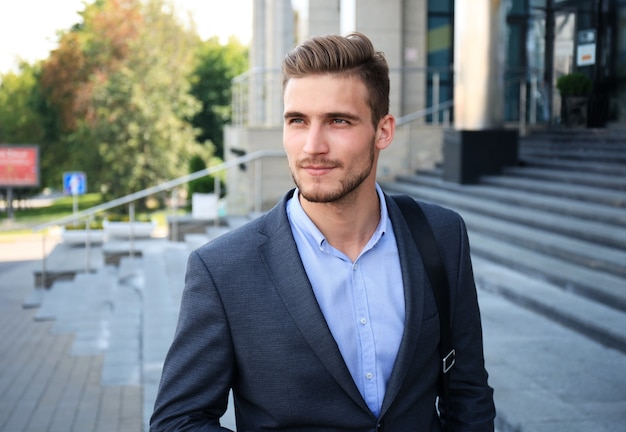 Retrato de un apuesto hombre de negocios en un traje de pie fuera de un edificio de la ciudad.