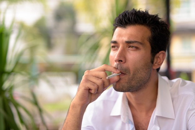 Retrato de apuesto hombre turco relajándose en la cafetería de la ciudad de Bangkok