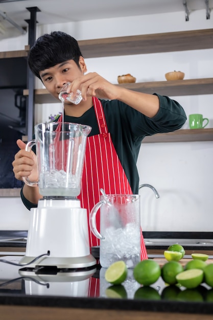 Retrato de un apuesto joven de Asia con una sonrisa feliz y vistiendo un delantal rojo en una cocina moderna.