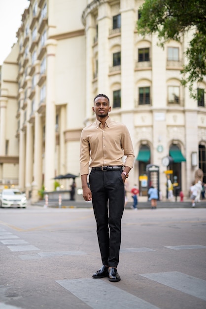 Retrato de apuesto joven empresario africano negro vistiendo ropa casual al aire libre en la ciudad