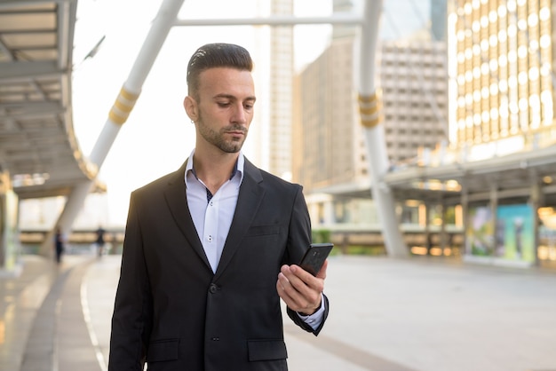 Retrato de apuesto joven empresario italiano al aire libre en la ciudad vistiendo traje