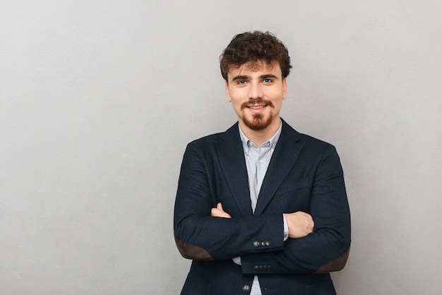 retrato de un apuesto joven hombre de negocios aislado sobre una pared gris.