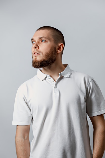 Foto retrato de un apuesto joven mirando atentamente al lado en blanco.