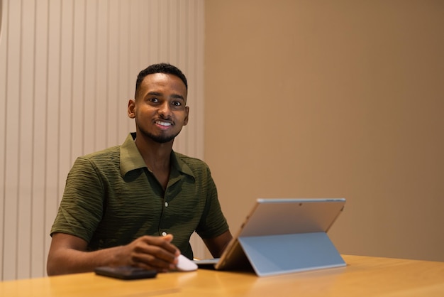 Retrato de un apuesto joven negro que usa una computadora portátil en una cafetería