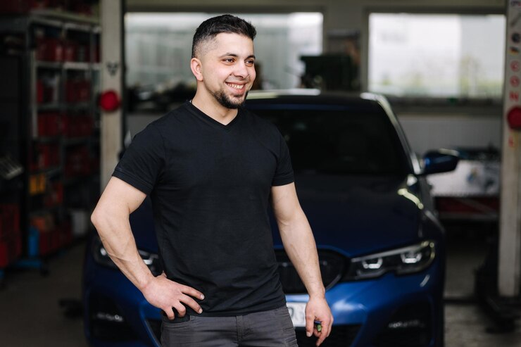 Foto retrato del apuesto propietario masculino del taller de reparación de automóviles mecánico barbudo en el trabajo en su garaje