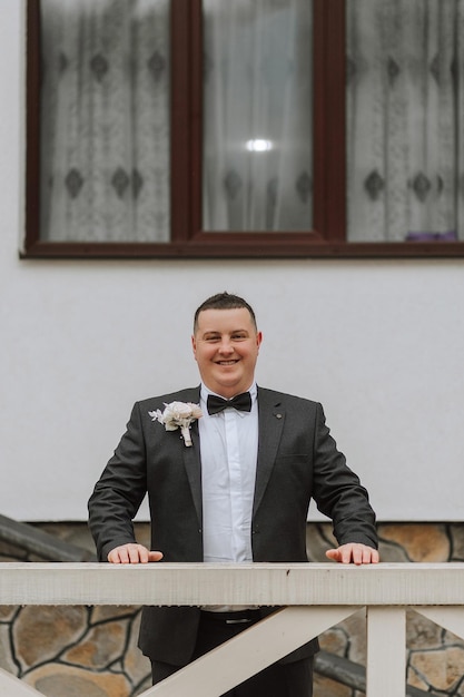 retrato de un apuesto y viril novio en un traje negro con una corbata novio en la naturaleza en la temporada de invierno