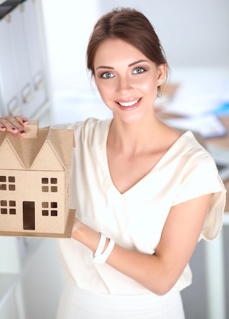 Retrato de una arquitecta sosteniendo una pequeña casa de pie en el cargo