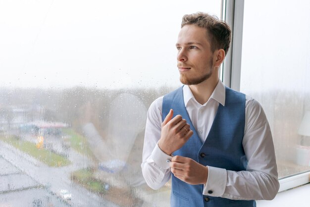 Retrato de un arrogante hombre vestido con traje azul que corrige el botón