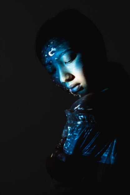 Retrato de arte Belleza cósmica Sabiduría del universo Silueta de cara de mujer alienígena asiática azul con luz de textura abstracta aislada sobre fondo negro