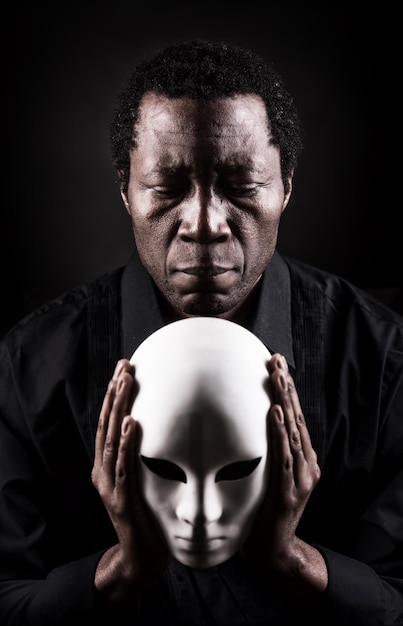 Retrato de arte dramático del hombre negro africano con máscara blanca