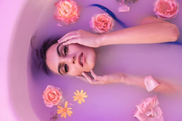 Retrato artístico desde arriba de un modelo en un baño de leche con flores