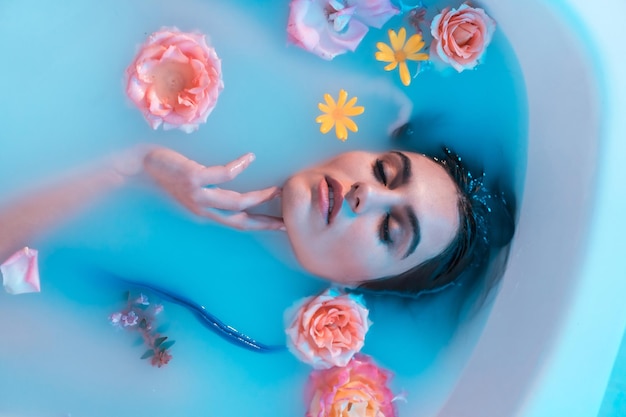 Retrato artístico de cima de uma bela mulher caucasiana em banho de leite florido